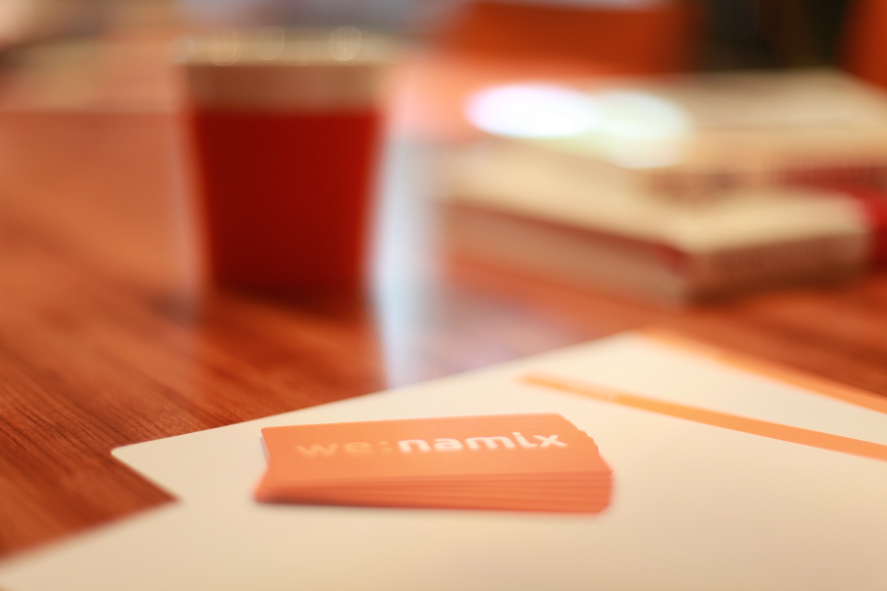 we:namix Visitenkarten auf einem Schreibtisch mit Notizbuch und Kaffeebecher